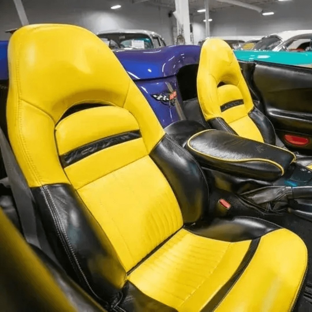 Corvette C5 interior with black and yellow leather seat covers featuring the Corvette emblem. The vibrant yellow and sleek black design enhance the sporty and luxurious feel of the car's cabin, providing a striking and comfortable upgrade. Detailed views showcase the high-quality materials and craftsmanship, adding a bold and eye-catching look to the vehicle's interior.