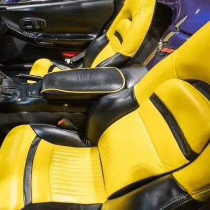 Corvette C5 interior with black and yellow leather seat covers featuring the Corvette emblem. The vibrant yellow and sleek black design enhance the sporty and luxurious feel of the car's cabin, providing a striking and comfortable upgrade. Detailed views showcase the high-quality materials and craftsmanship, adding a bold and eye-catching look to the vehicle's interior.